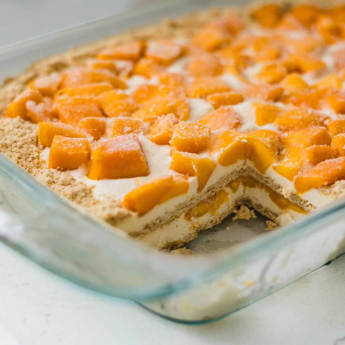 Homemade mango float sliced in a glass baking dish