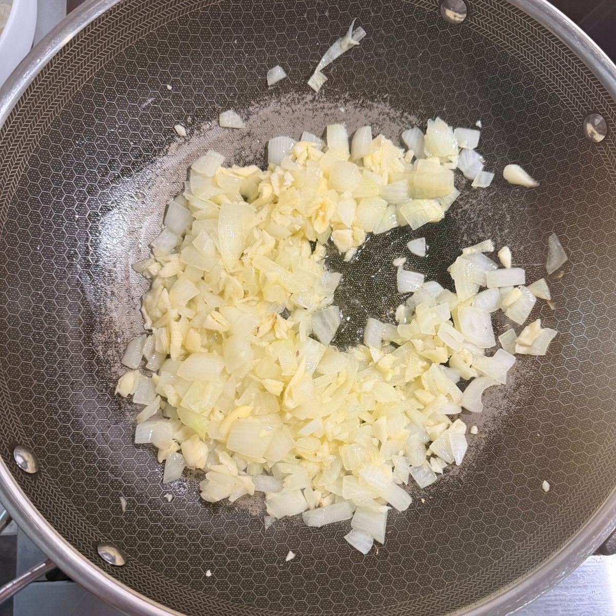 Chopped garlic and onion sautéing in a pan for Filipino spaghetti