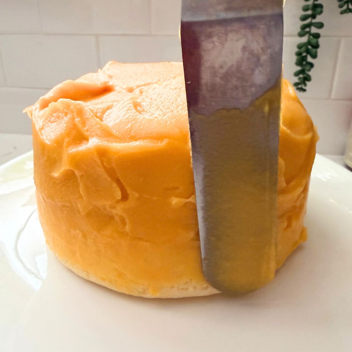Offset spatula spreading yema frosting over the top and sides of a round cake.