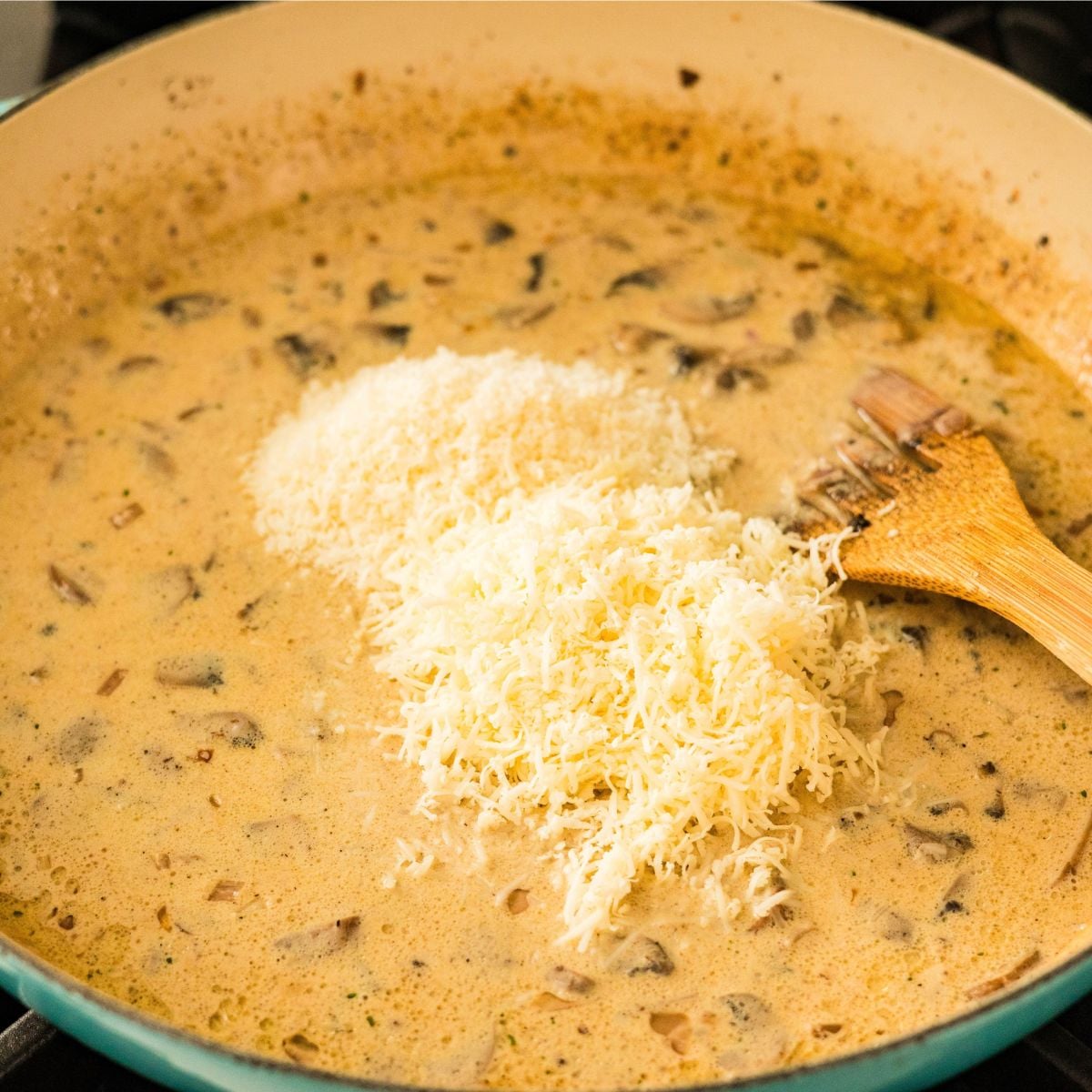Grated cheese being added to creamy carbonara sauce