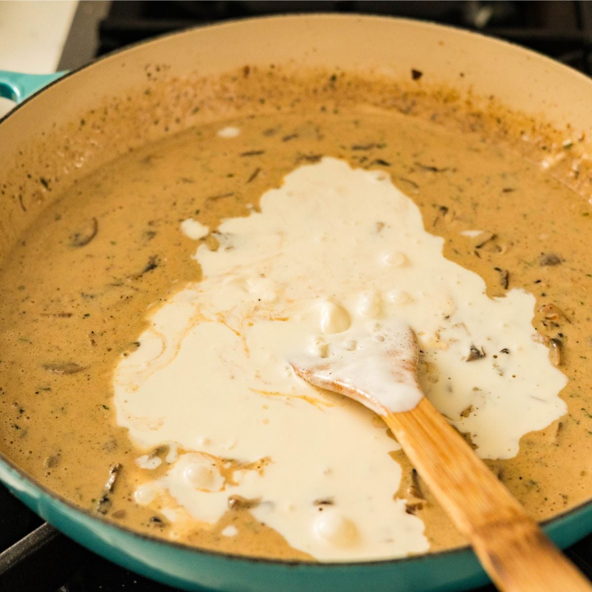 Cream being added to the mushroom and bacon carbonara sauce