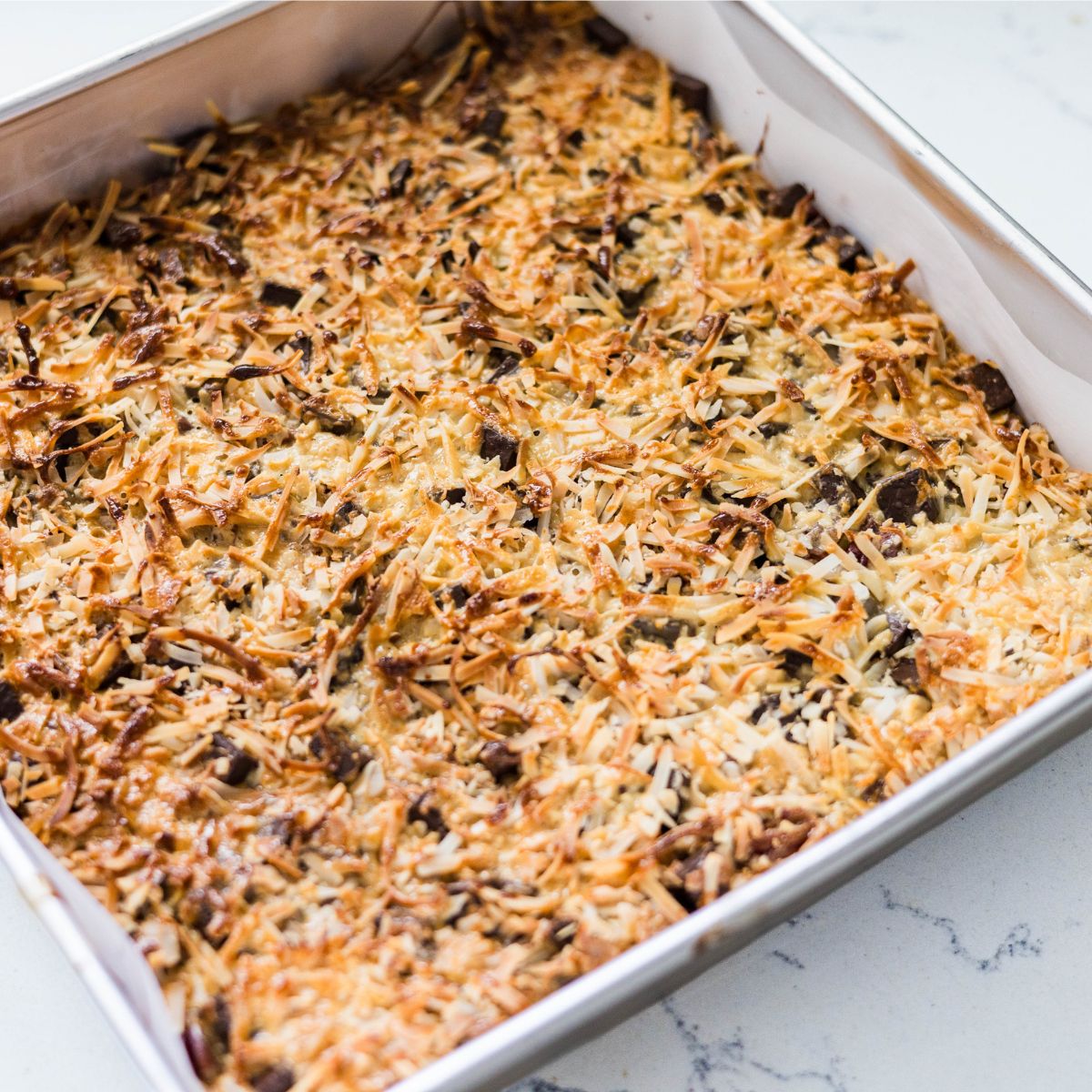 Baked magic cookie bars with a golden toasted coconut top
