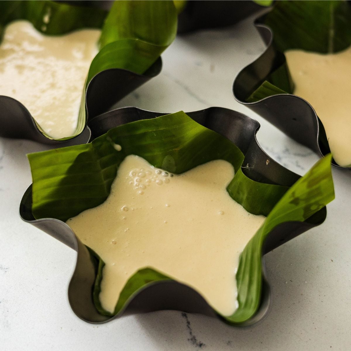 Bibingka batter poured into a banana leaf lined baking mold
