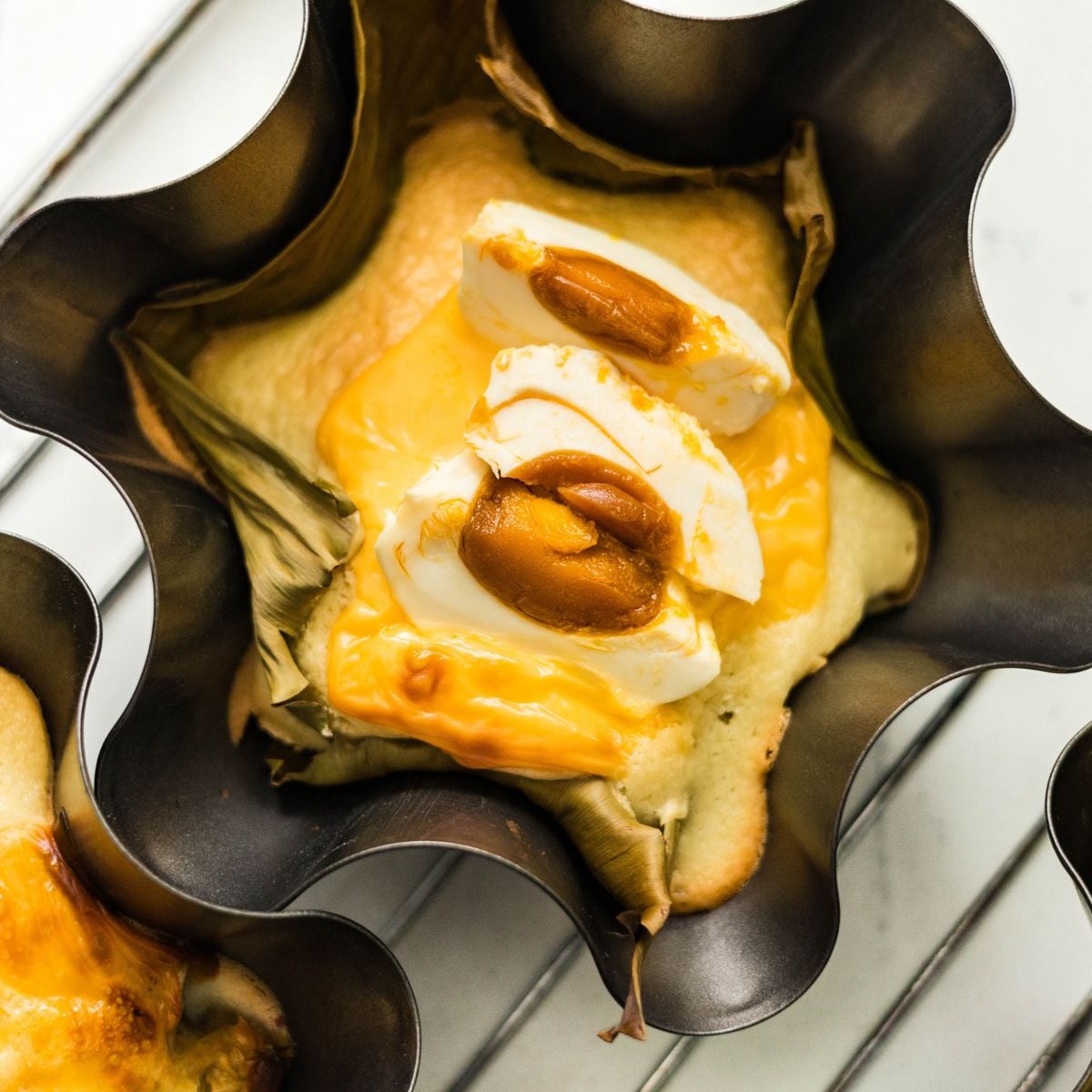 Close up of Filipino bibingka topped with melted cheese and salted egg