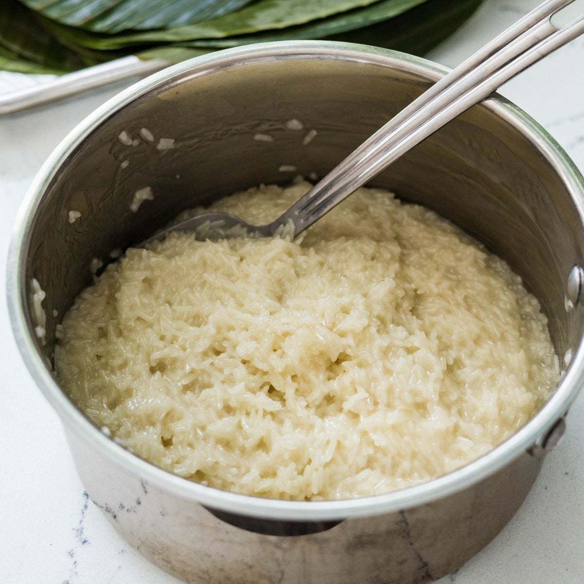 Partially cooked sweet rice cooling before rolling into suman