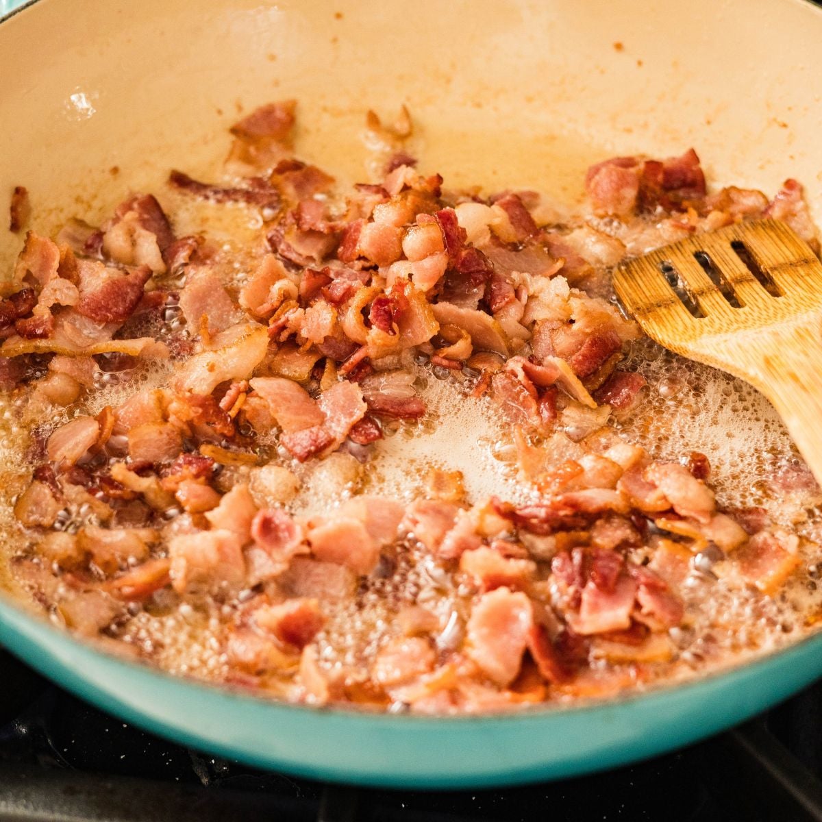 Chopped bacon cooking in a pan until lightly crisp