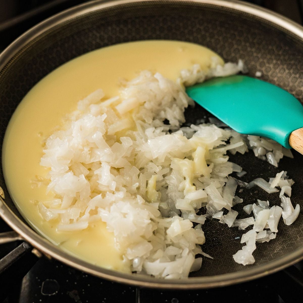 Macapuno strings and sweetened condensed milk cooking together in a pan