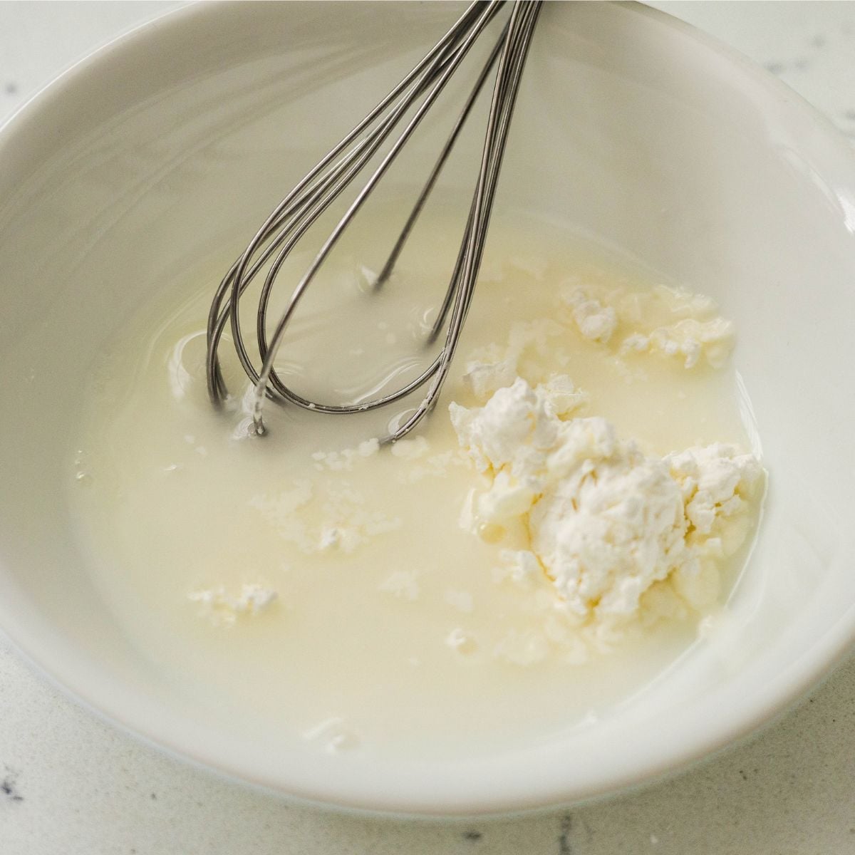 Cornstarch and water slurry being whisked until smooth