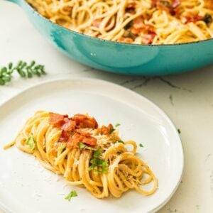 Creamy carbonara pasta served on a white plate with bacon and parsley
