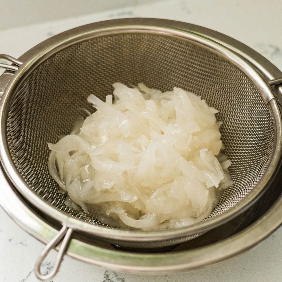 Well-drained macapuno strings in a fine mesh strainer