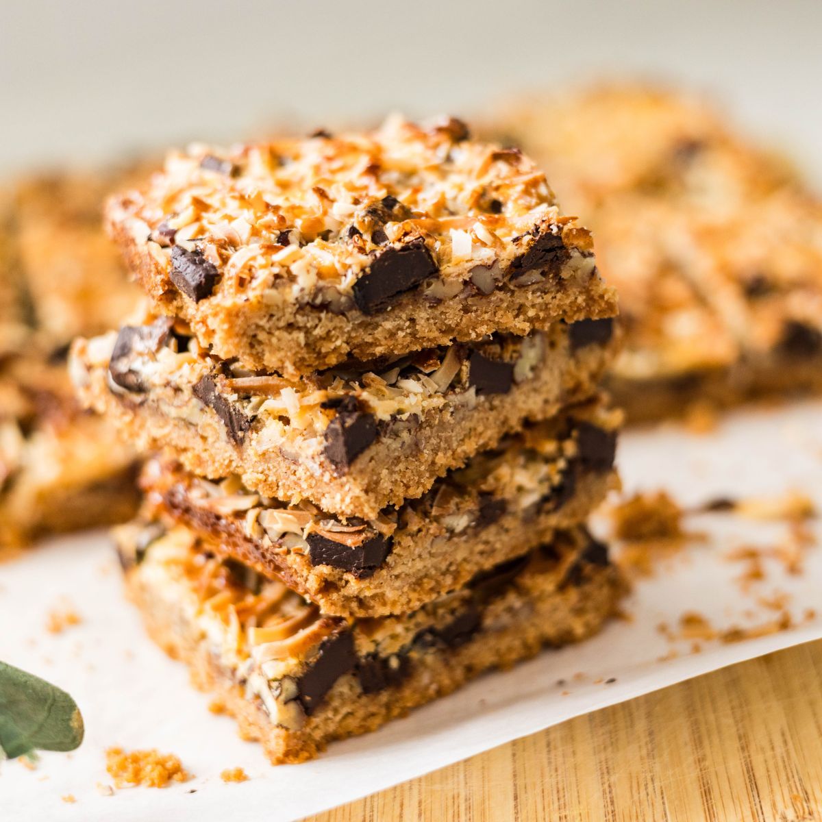Easy magic cookie bars stacked high, showing the chewy condensed milk layer between the crust and coconut topping