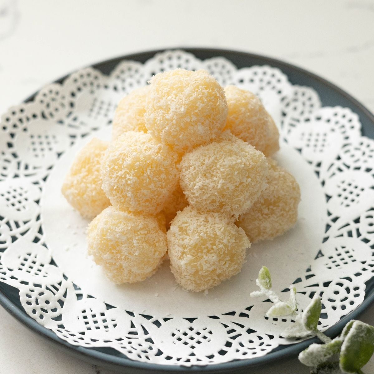 Macapuno coconut balls coated in desiccated coconut on a white plate