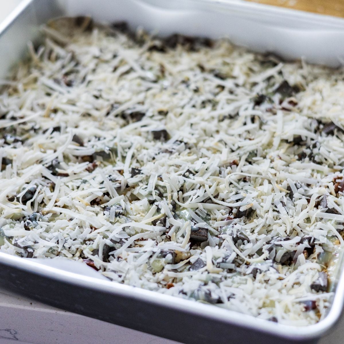 Shredded coconut sprinkled over the condensed milk layer before baking magic cookie bars