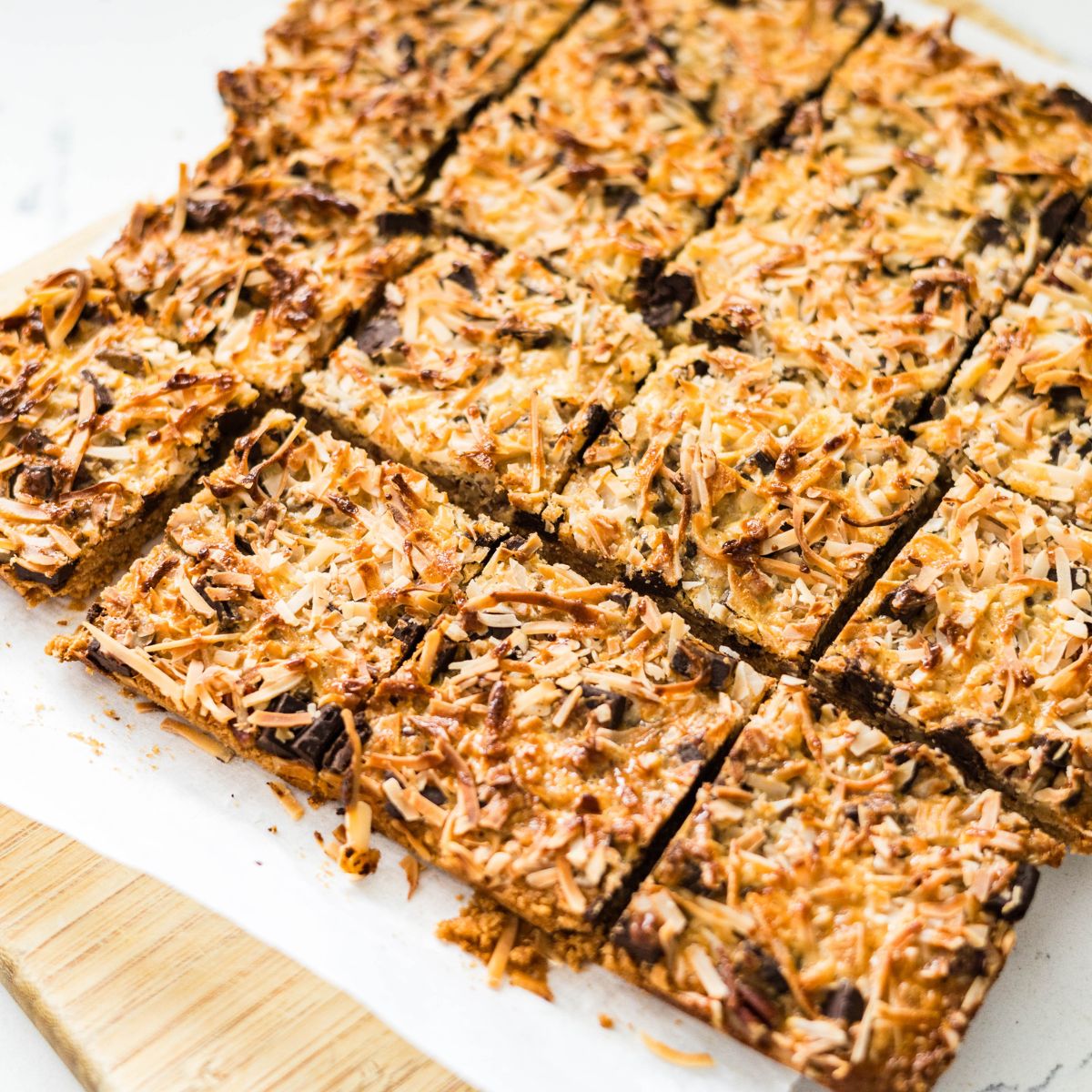 Baked magic cookie bars cut into squares with a golden toasted coconut top