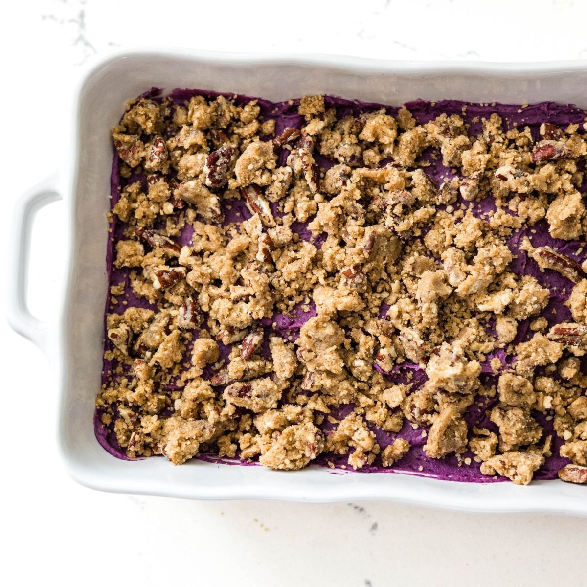 Purple sweet potato casserole topped with pecan streusel before baking