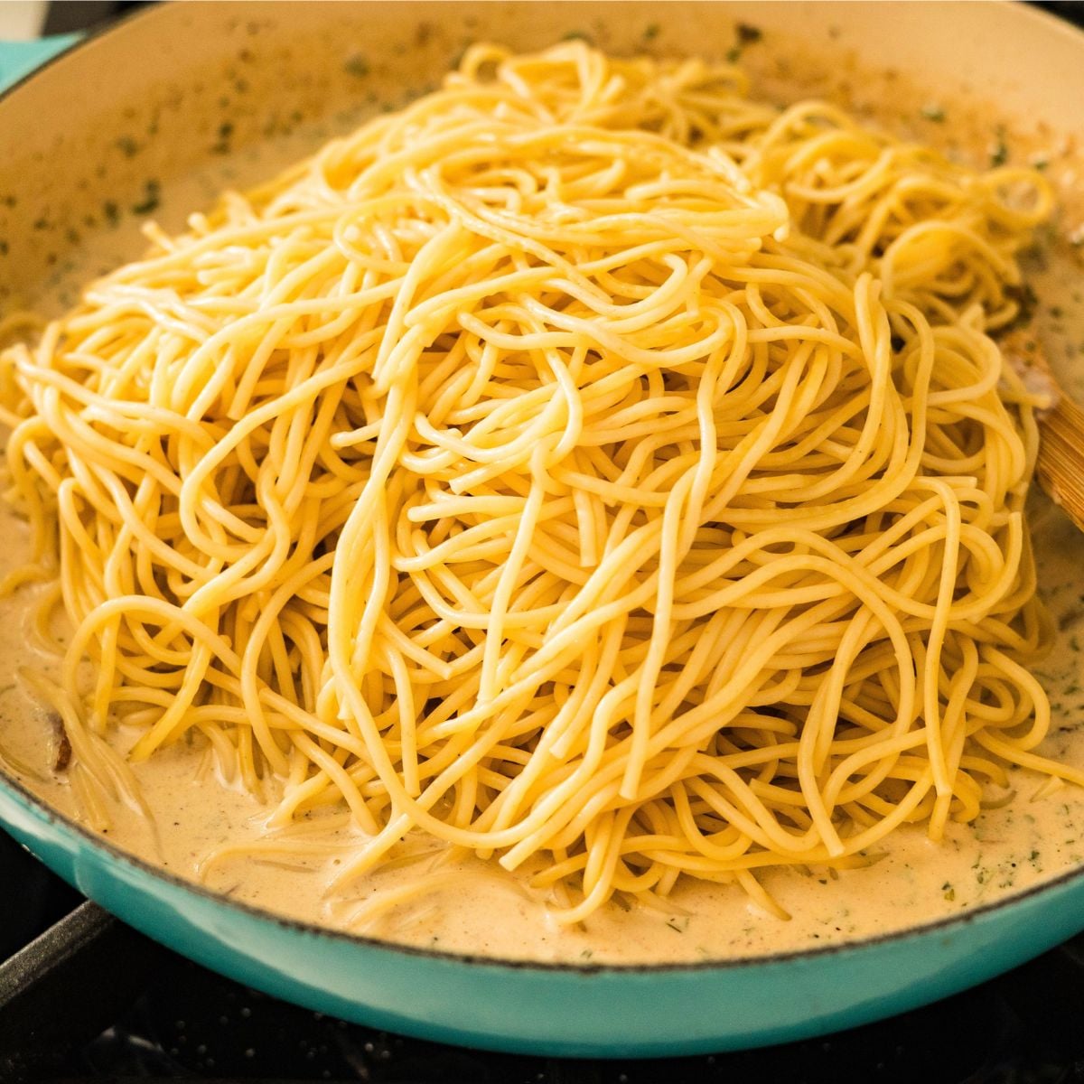 Spaghetti being tossed in creamy Filipino-style carbonara sauce