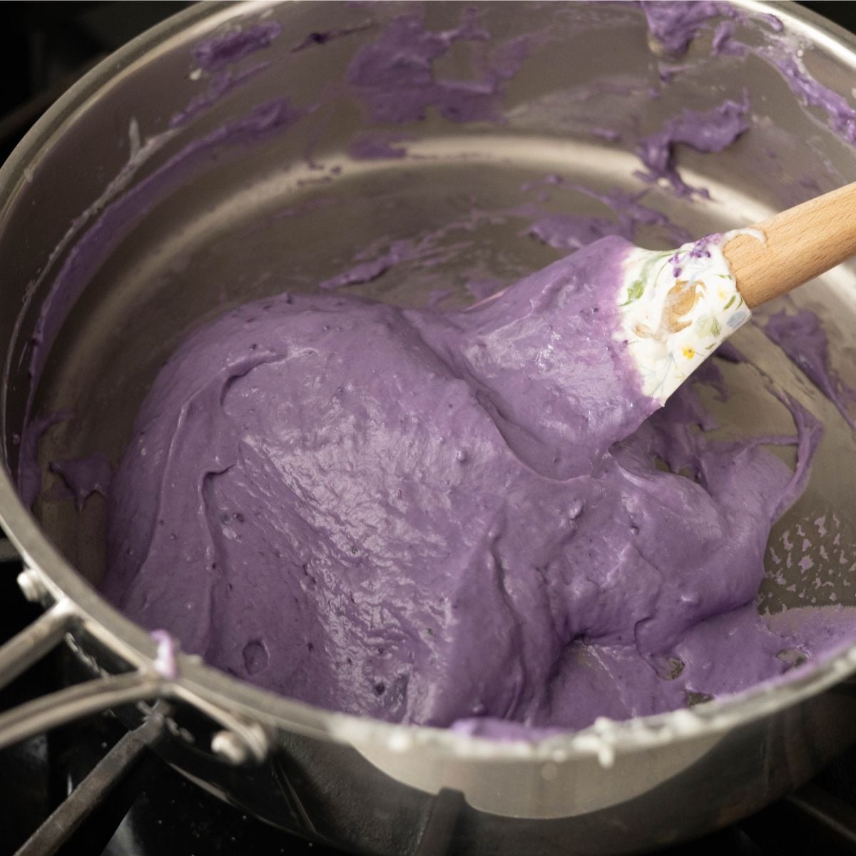 Thick purple ube inutak mixture being stirred in a pan