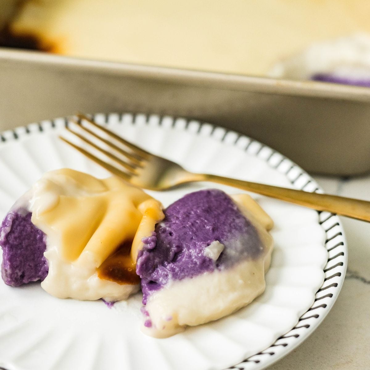 Slice of ube inutak with purple and creamy coconut layers on a white plate