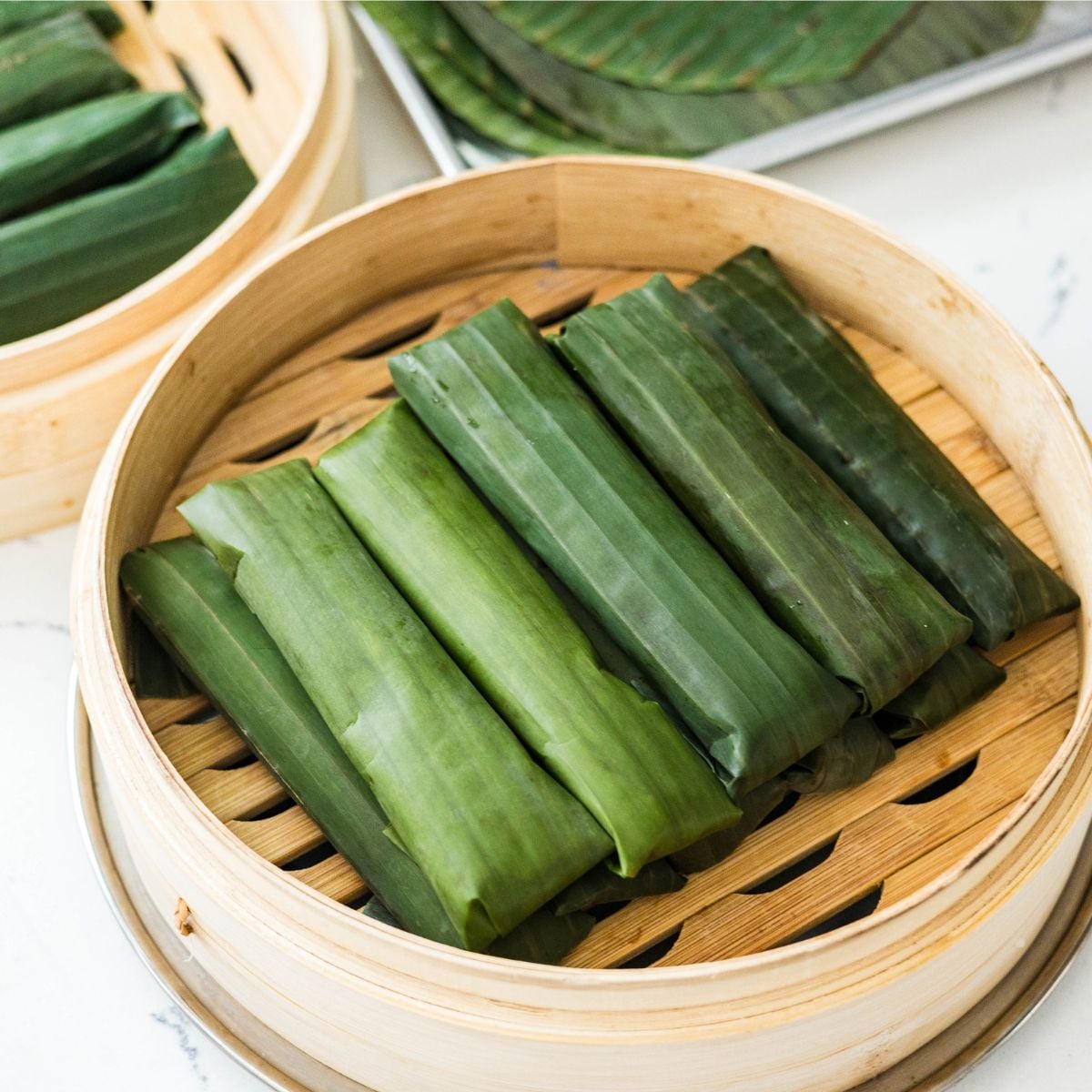 Banana leaf-wrapped suman malagkit arranged in a steamer basket